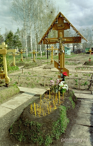 Могила отца Владимира (Шикина). Свечи, записочки с просьбами, заткнутые за распятие. Внизу к кресту прибита иконка царя Николая