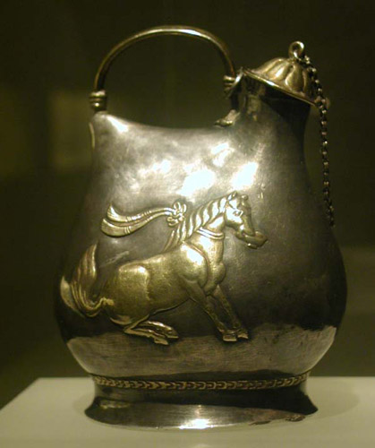 Серебряный с позолотой сосуд эпохи Тан (VIII в.) с изображением одного из танцующих коней императора Сюаньцзуна. Этот конь весьма ловок, он танцует с чашей во рту